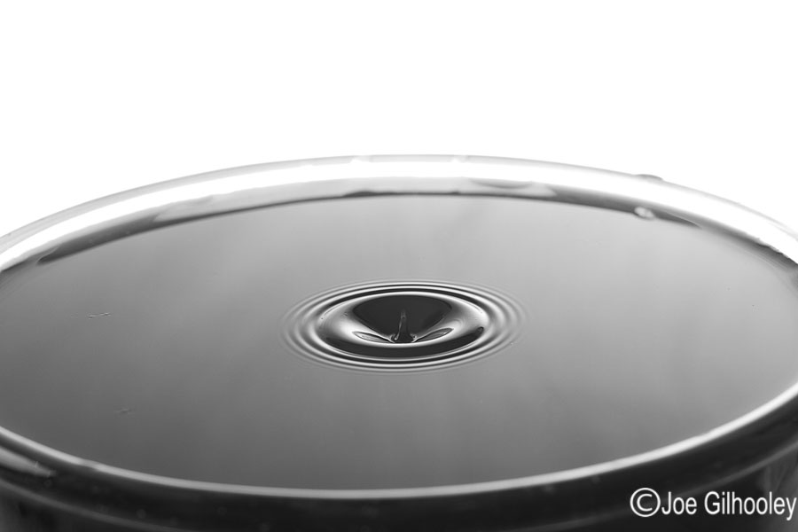Dropping Water Droplets into coloured water in glass bowl