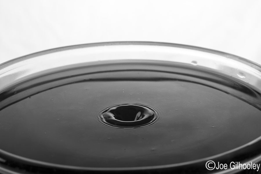 Dropping Water Droplets into coloured water in glass bowl